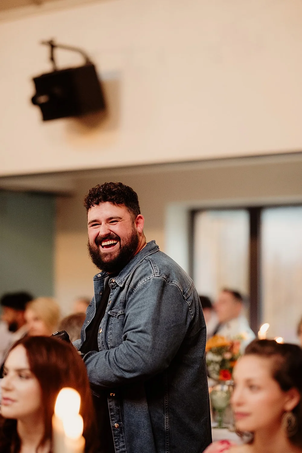 A Bokeh photographer laughing with guests during a wedding reception
