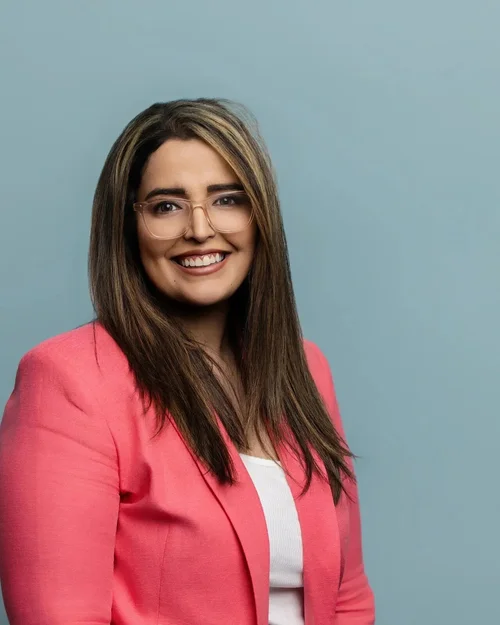 Corporate team headshot of a woman in a pink blazer on a teal backdrop for Fluor in Greenville, SC