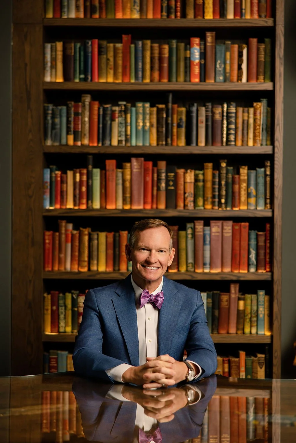 Allen Clardy seated at a reflective table in front of bookshelves at the Bohemian