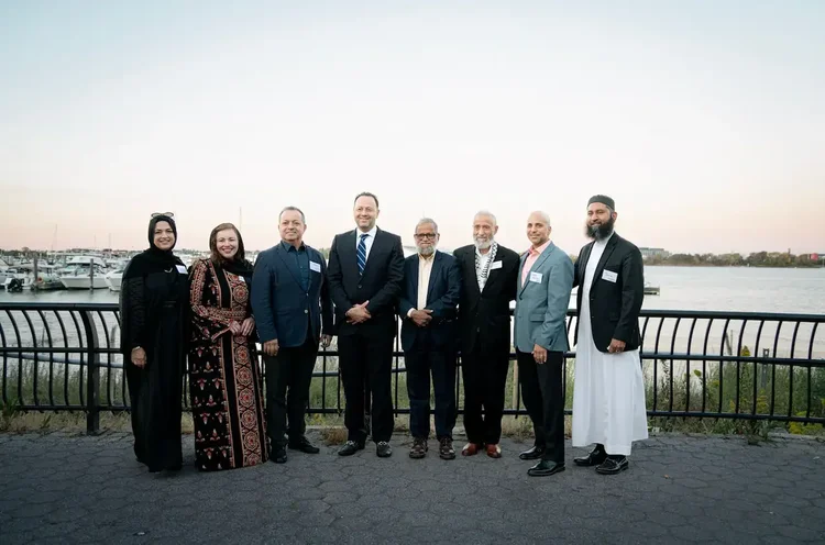 Eight honorees and CAIR-NY leaders standing together at the marina railing at sunset