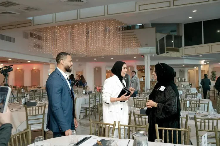Three guests talking beside the set tables before the program begins