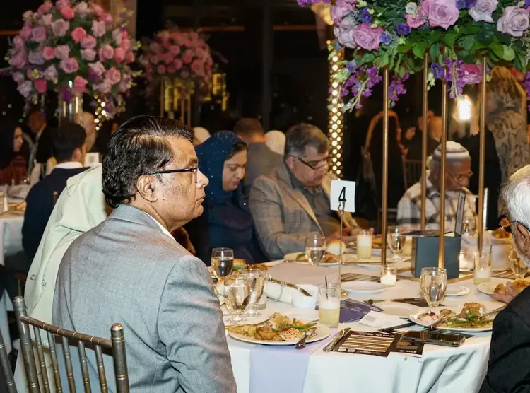 Guests seated at table four following the program, pink and lilac centerpieces overhead