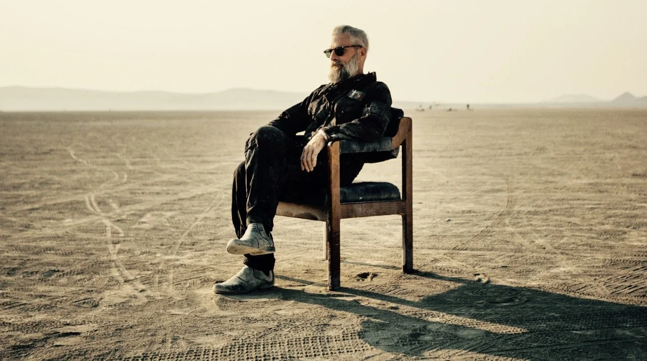 chris berlin seated alone in a chair on the open playa