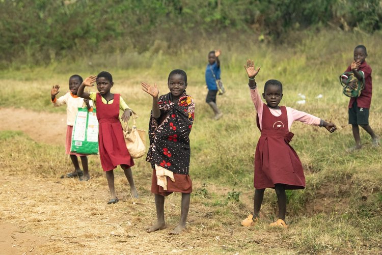 Kids waving on a dirt road in Malawi