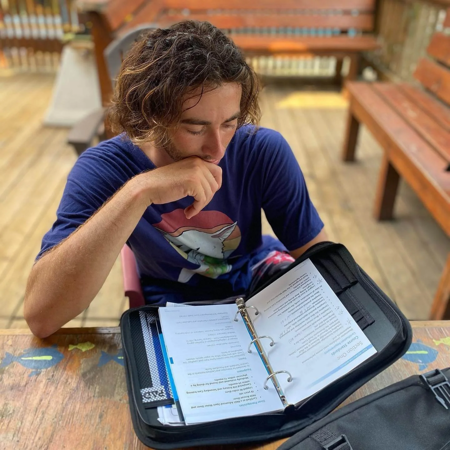 A Divemaster candidate studying course materials in preparation for the PADI Divemaster examination.