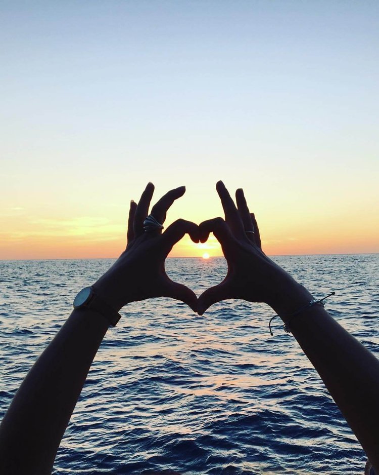 Divemaster trainee making a heart sign to the sunset, Roatan