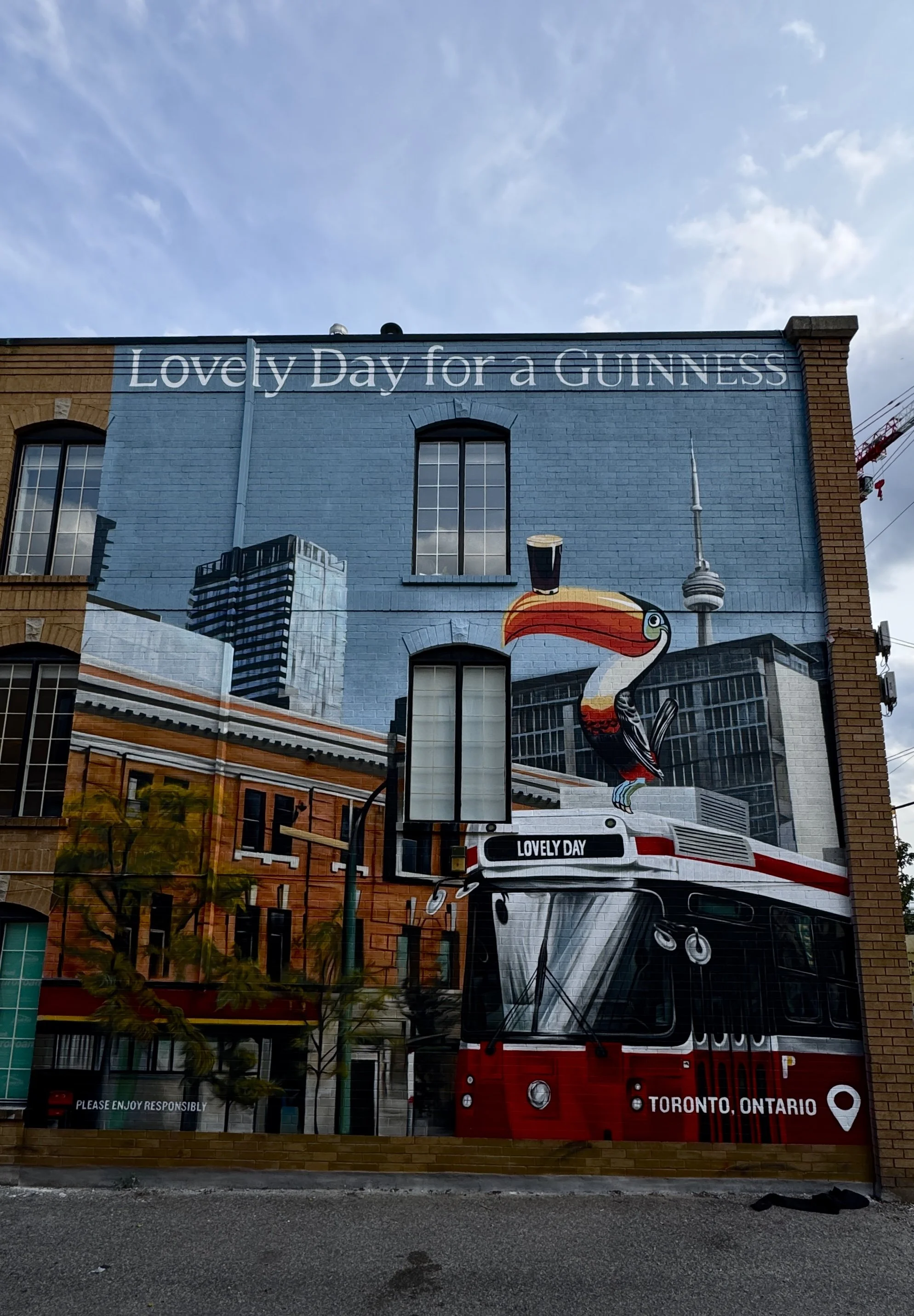 Guinness mural on a Toronto brick building, featuring a toucan, streetcar and CN Tower