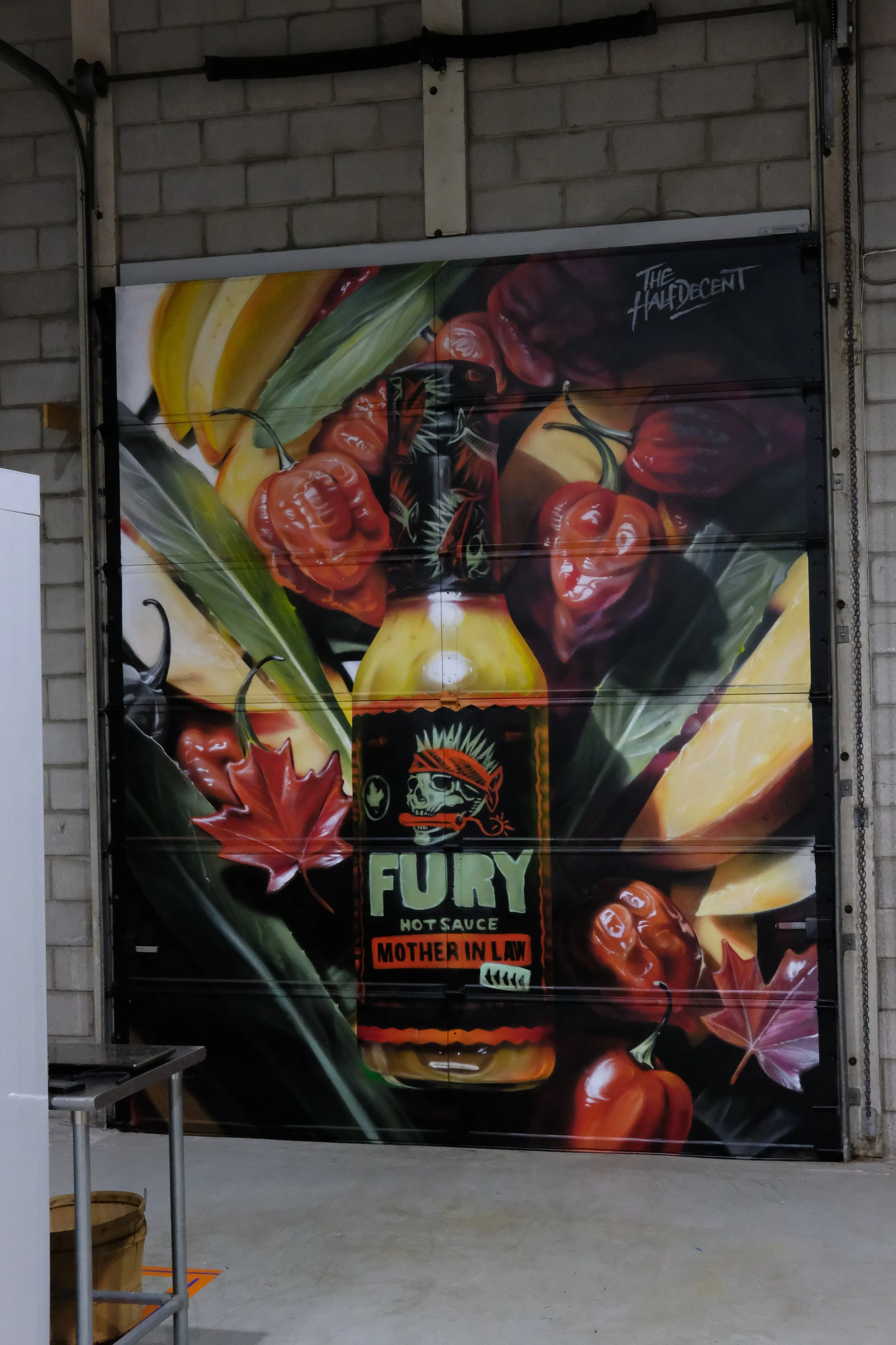 FURY Hot Sauce mural on a garage door, featuring a sauce bottle, peppers and tropical fruit
