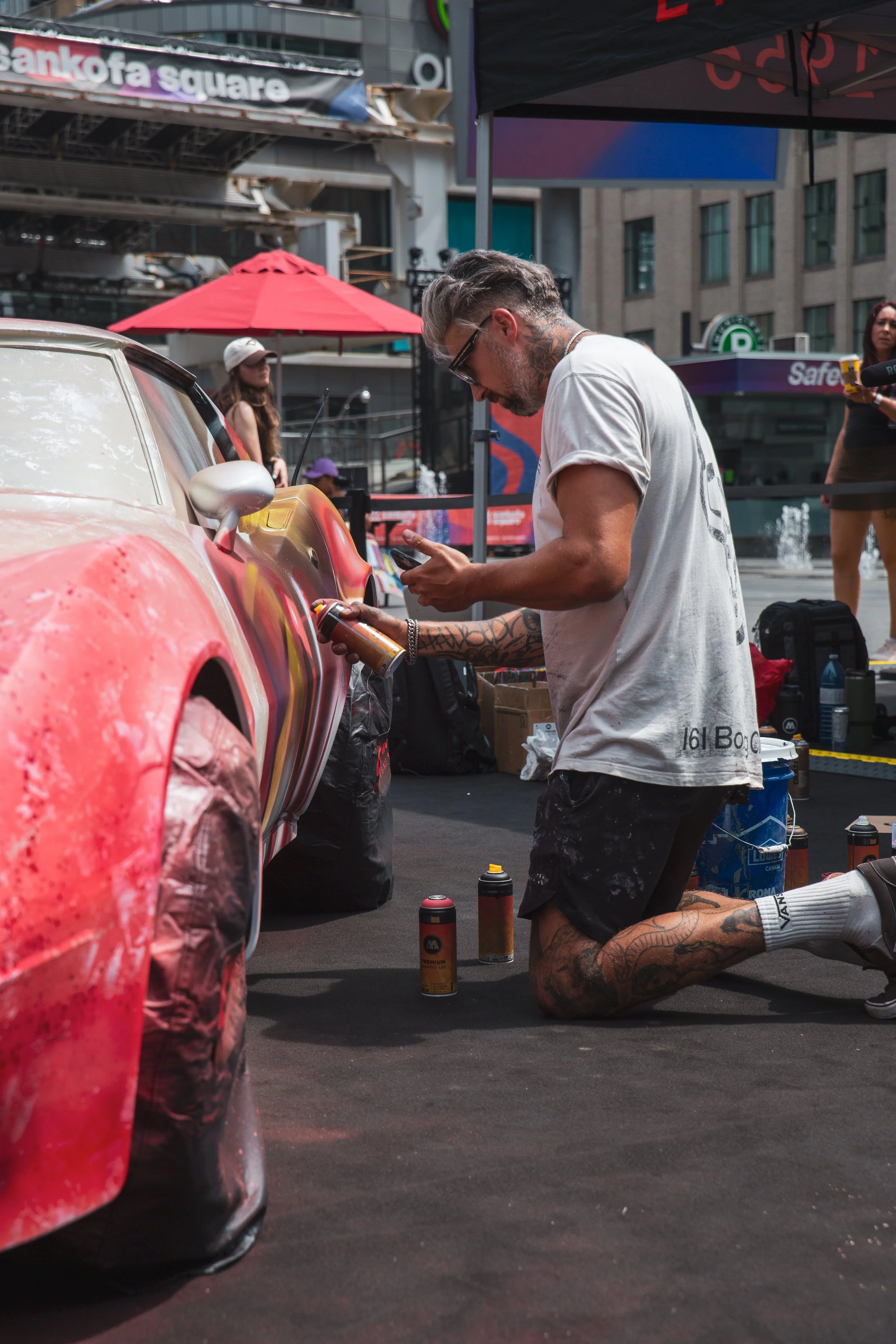 Close view of TheHalfDecent spray-painting the side of a car for Carrera