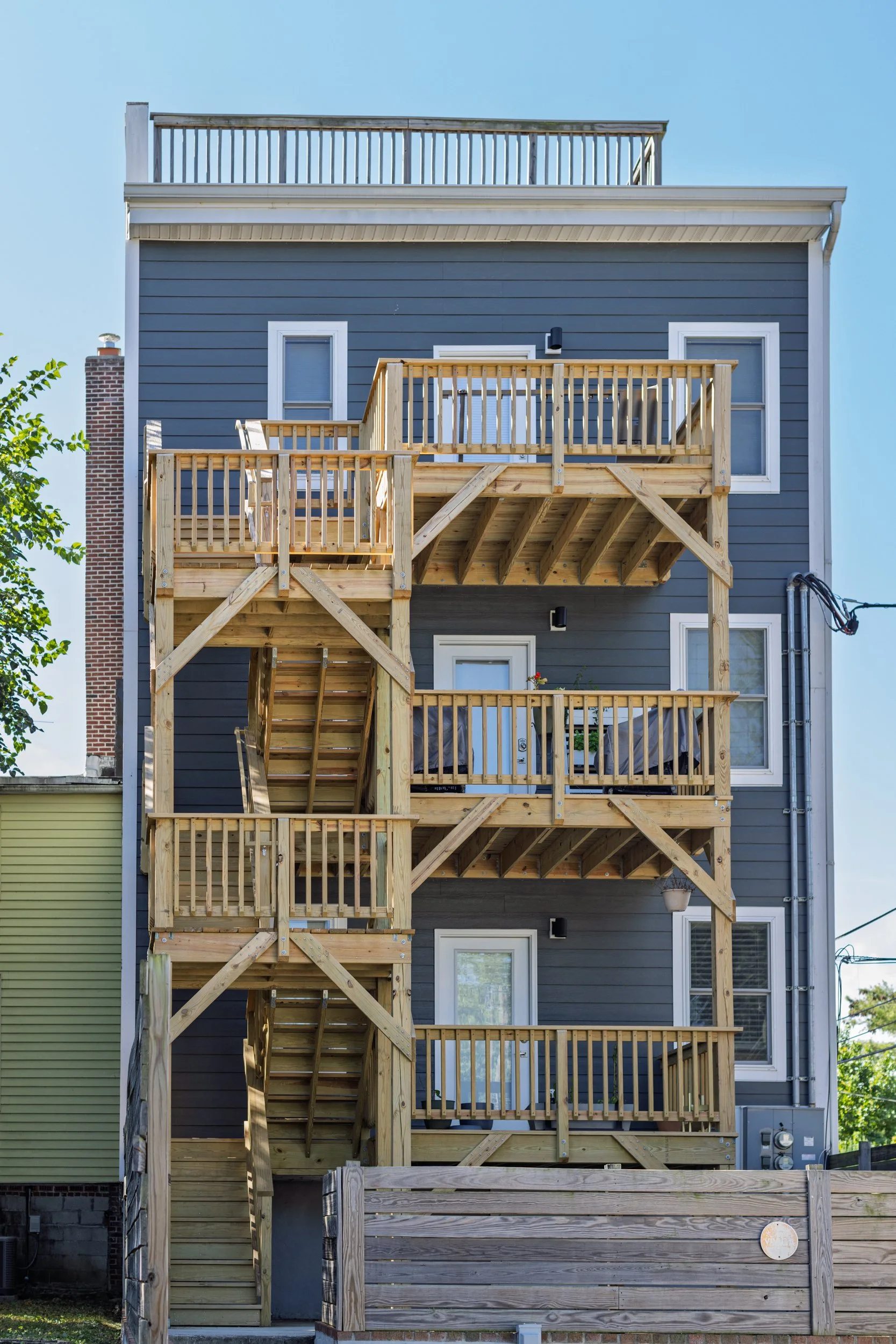 Exterior wood stairs and landings beside blue-gray siding.