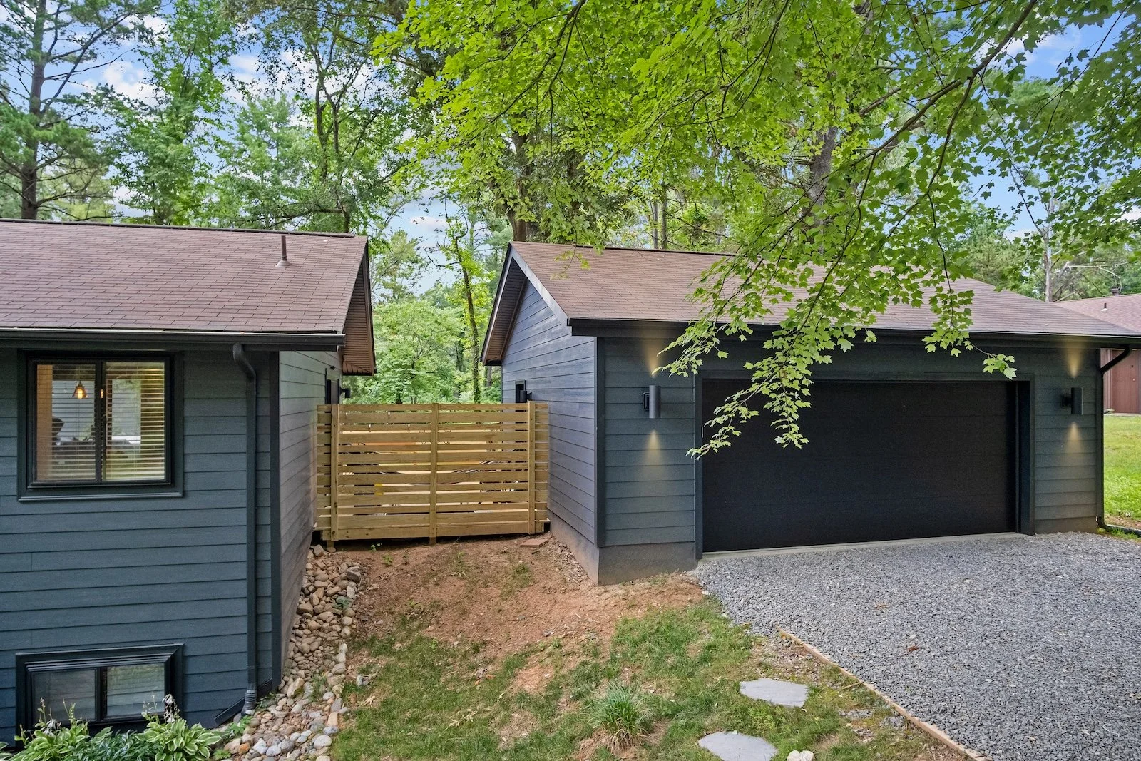 Pia’s garage addition with dark siding and a black garage door