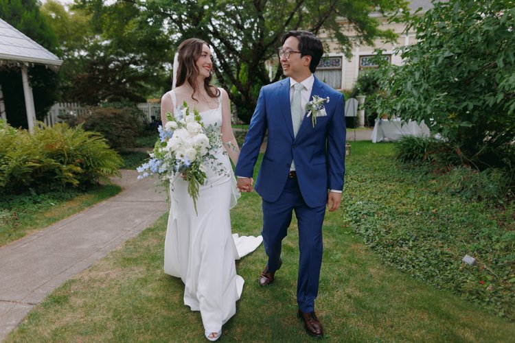 A bride and groom walk hand-in-hand on their wedding day.