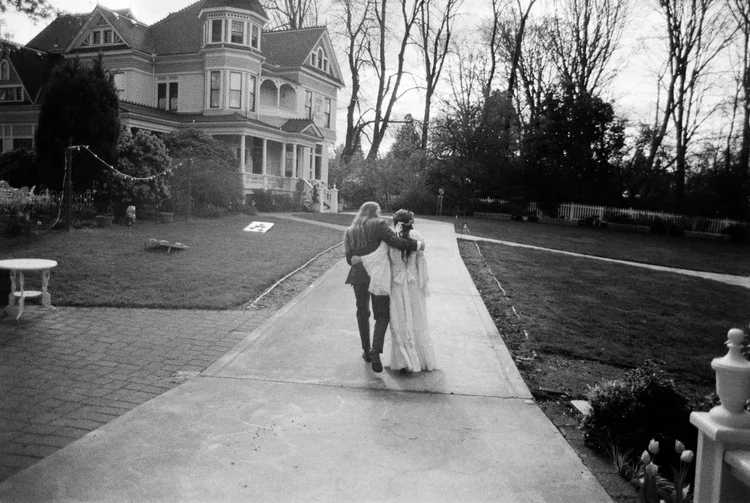 A bride and groom walk arm-in-arm on their wedding day.