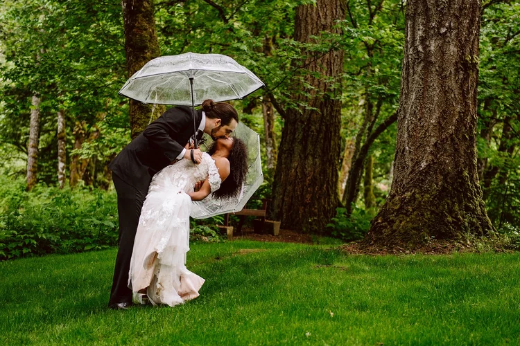 A couple kisses in the rain on their wedding day.