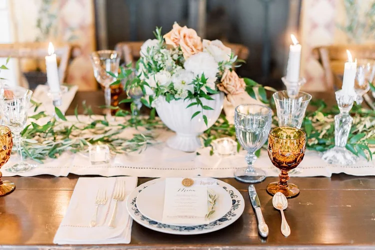 A dinner table set with vintage glassware and china.
