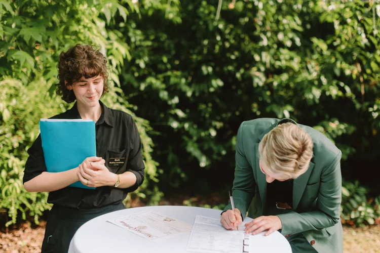A wedding planner and guest work on the marriage license.