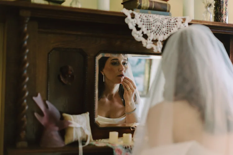 A bride applies lip stick on her wedding day.