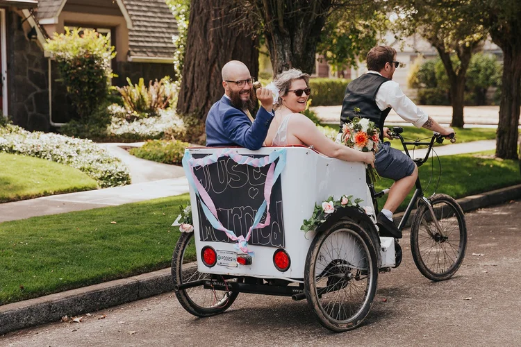 A bride and a groom ride in a bike trolly on their wedding day.