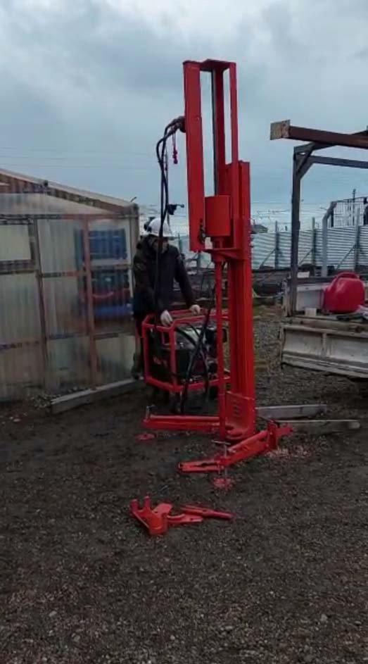Equipo rojo de ensayo SPT instalado sobre el terreno, con un operador a su lado.