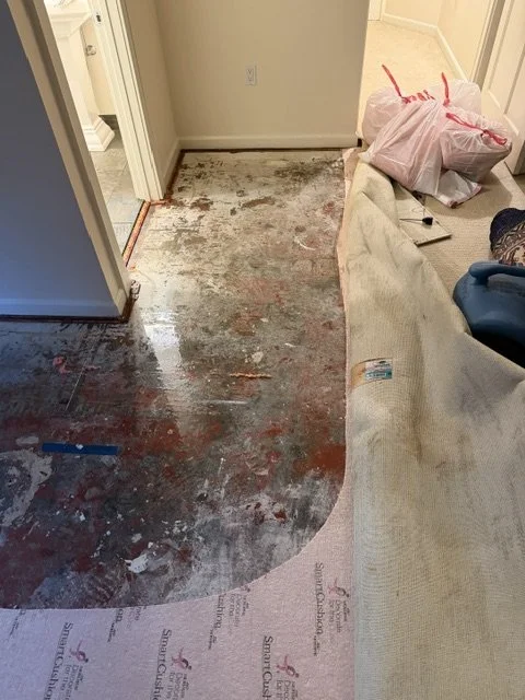 Carpet pulled back and soaked carpet pad removed in a flooded Lake Oswego bedroom