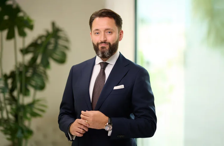 Portrait of a bearded financial professional in a navy suit.