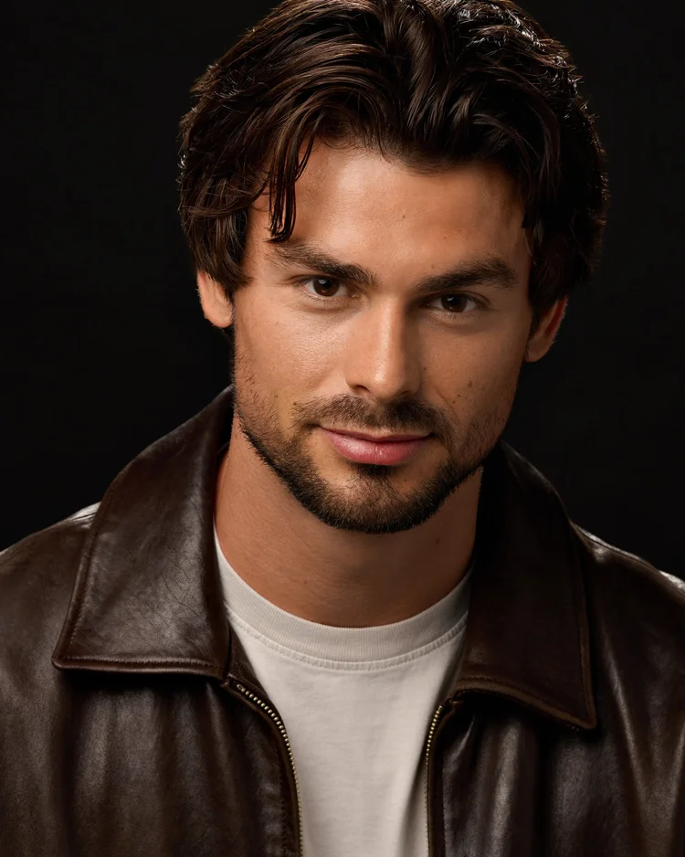 Actor headshot of a bearded man in a dark jacket.