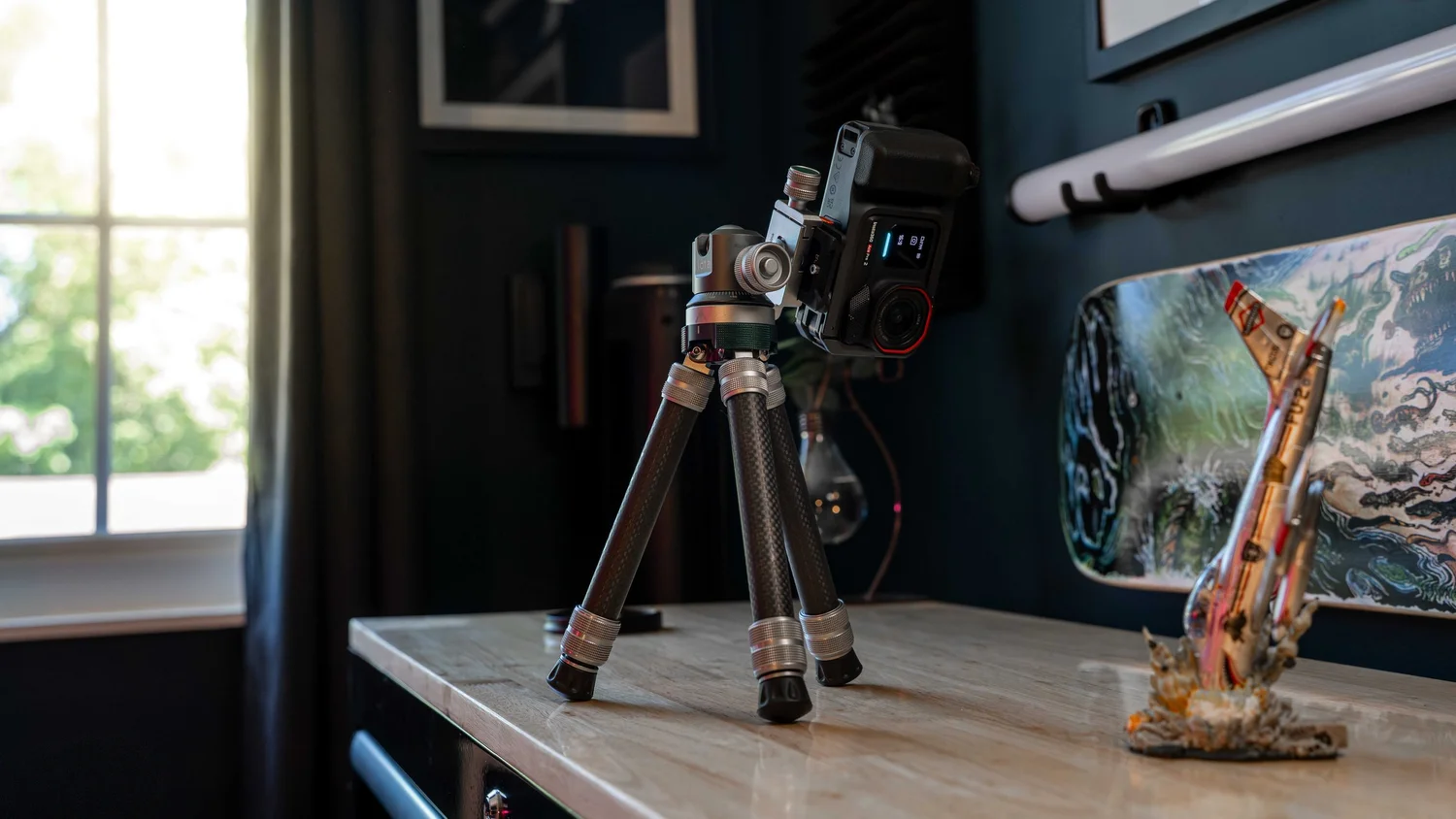 ProMaster iota 219 carbon fiber tripod holding an action camera on a butcher block counter beside a window