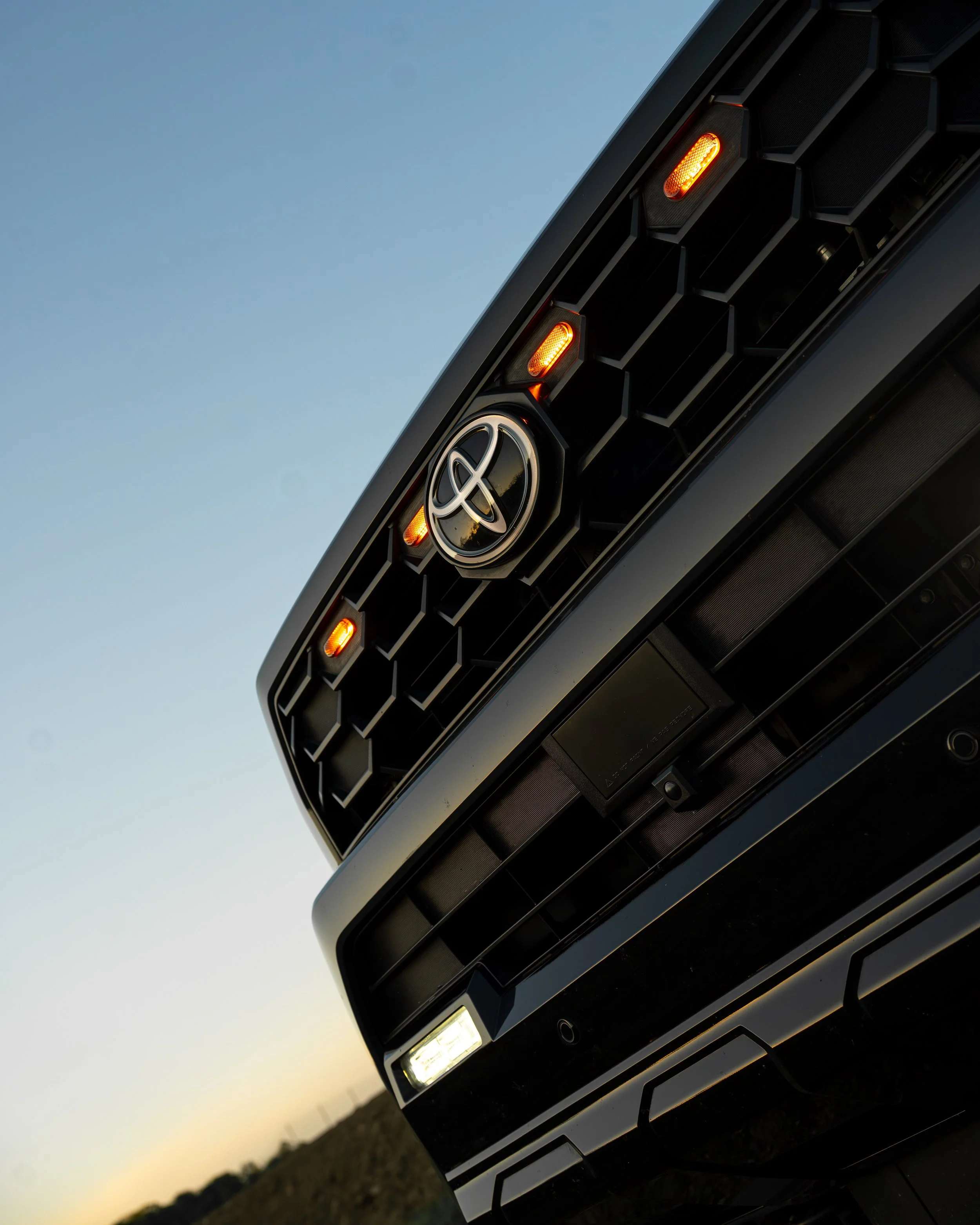 Low-angle close-up of a Toyota 4Runner front grille with amber marker lights, photographed by Ian Jones of ISJDESIGNS for the Tamron 35-100mm review.