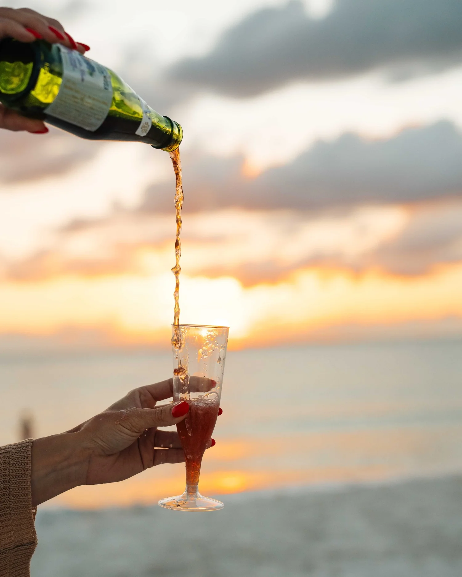 Wine pouring into a glass against a Gulf Coast sunset, beverage and hospitality lifestyle photography for hotels, resorts, restaurants, and destination brands.