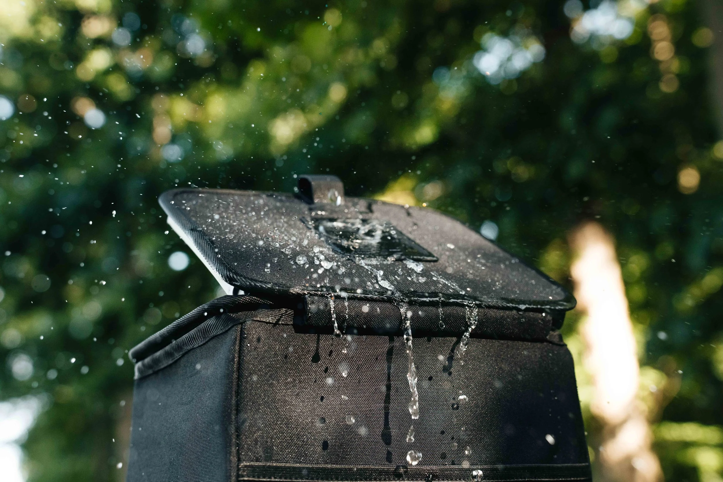 Water splashing over the black Double Deez Goodz car trash can outdoors, commercial product photography by Ian Jones of ISJDESIGNS.