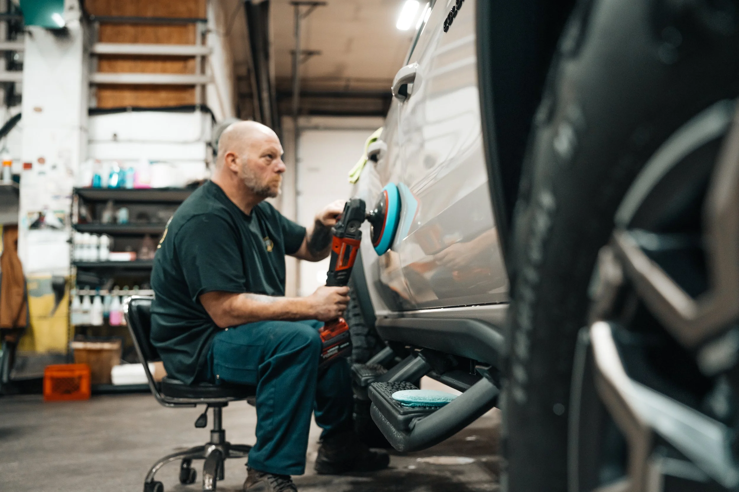 Commercial photography of an automotive detailing technician polishing a truck inside a Pittsburgh garage