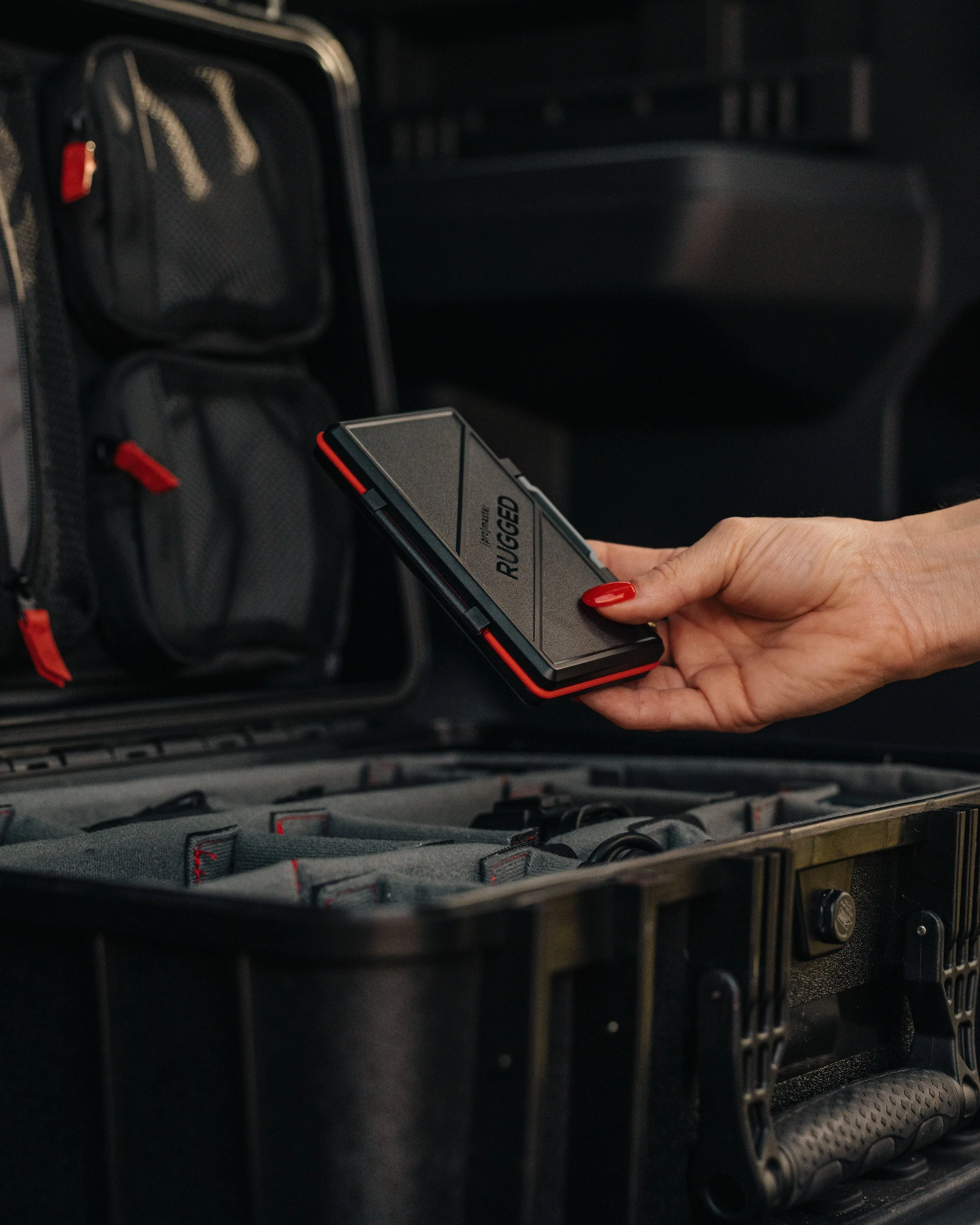 Lifestyle product photography of a ProMaster Rugged memory card case being placed inside a protective gear case