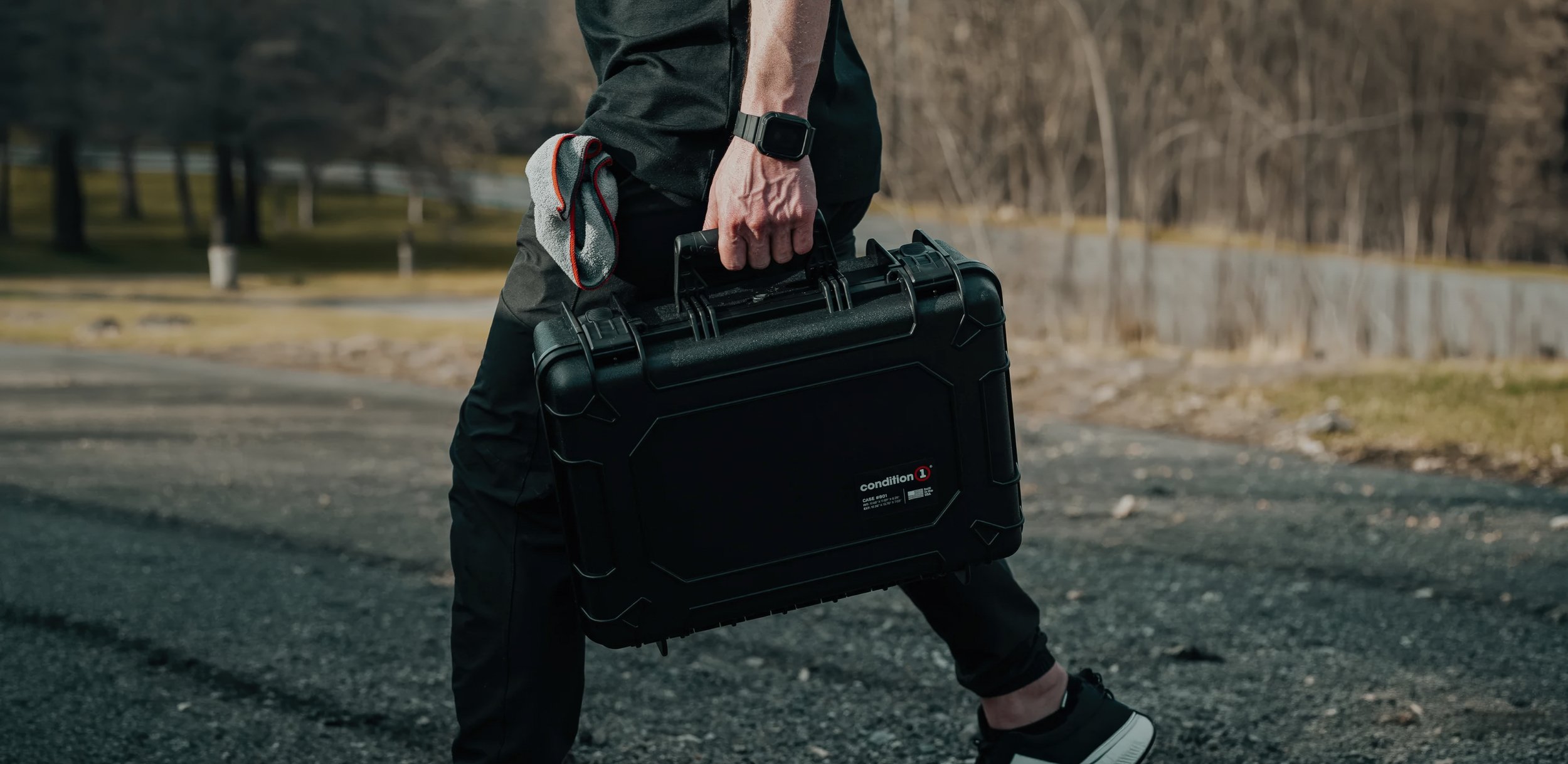 Lifestyle product photography of a rugged black Condition 1 protective hard case carried outdoors