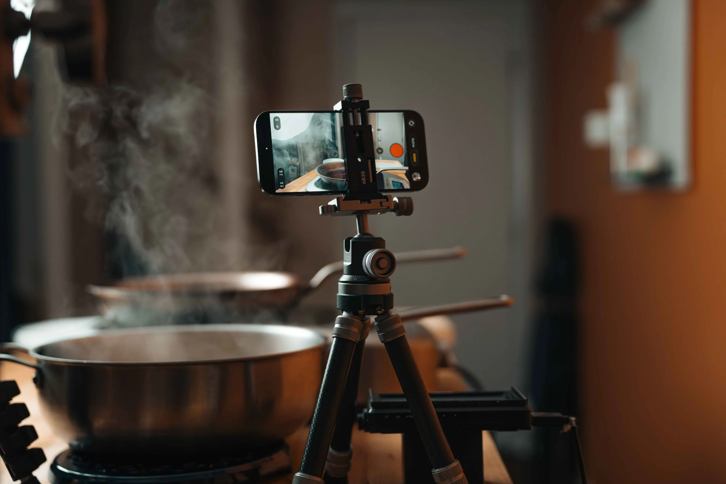 ProMaster iota 219 tabletop tripod filming a steaming pot on a stovetop in a warm-lit kitchen