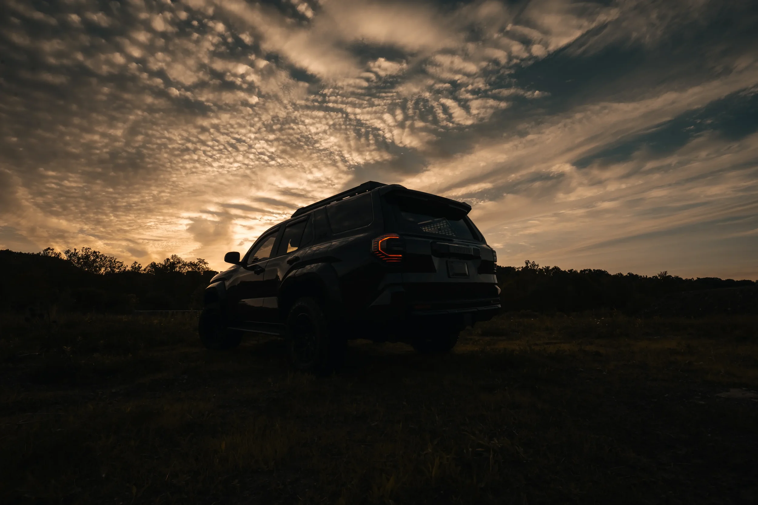 2025 Toyota 4Runner TRD Sport in Underground seen from the rear at sunset under a dramatic cloud-filled sky.
