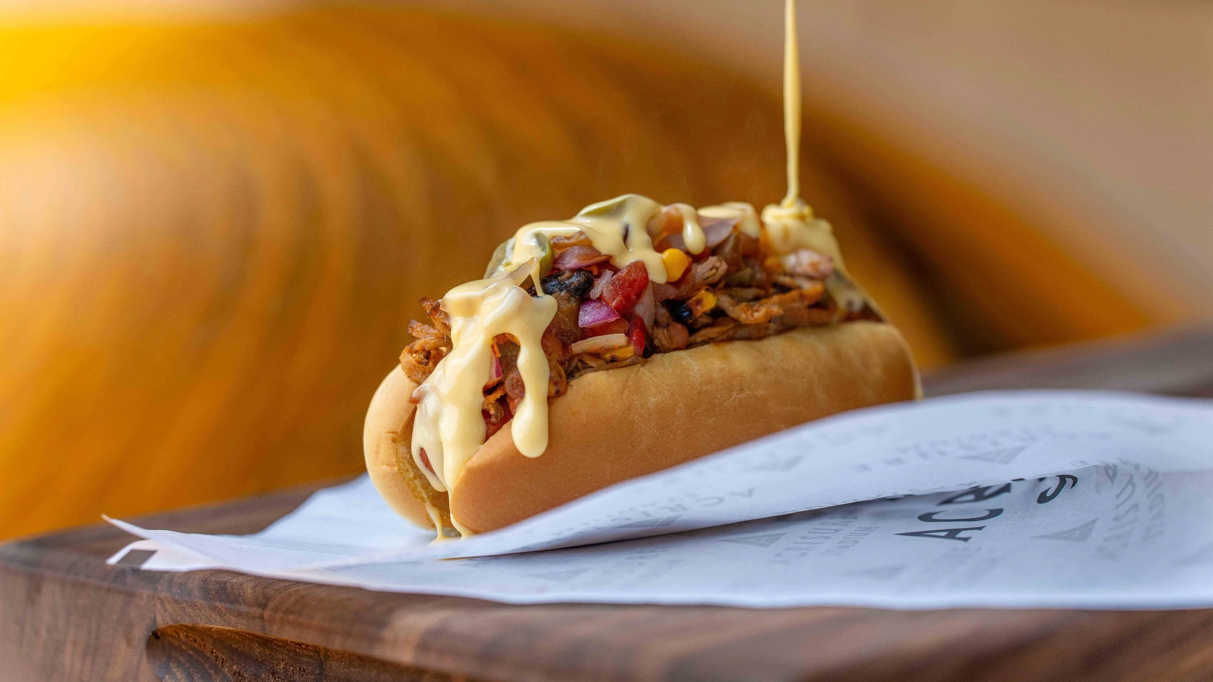 Pittsburgh food photography of the Cowpoke Dog hot dog with pulled pork, salsa, jalapeño, cheese sauce, and avocado crème at Acrisure Stadium for Aramark by Ian Jones of ISJDESIGNS.