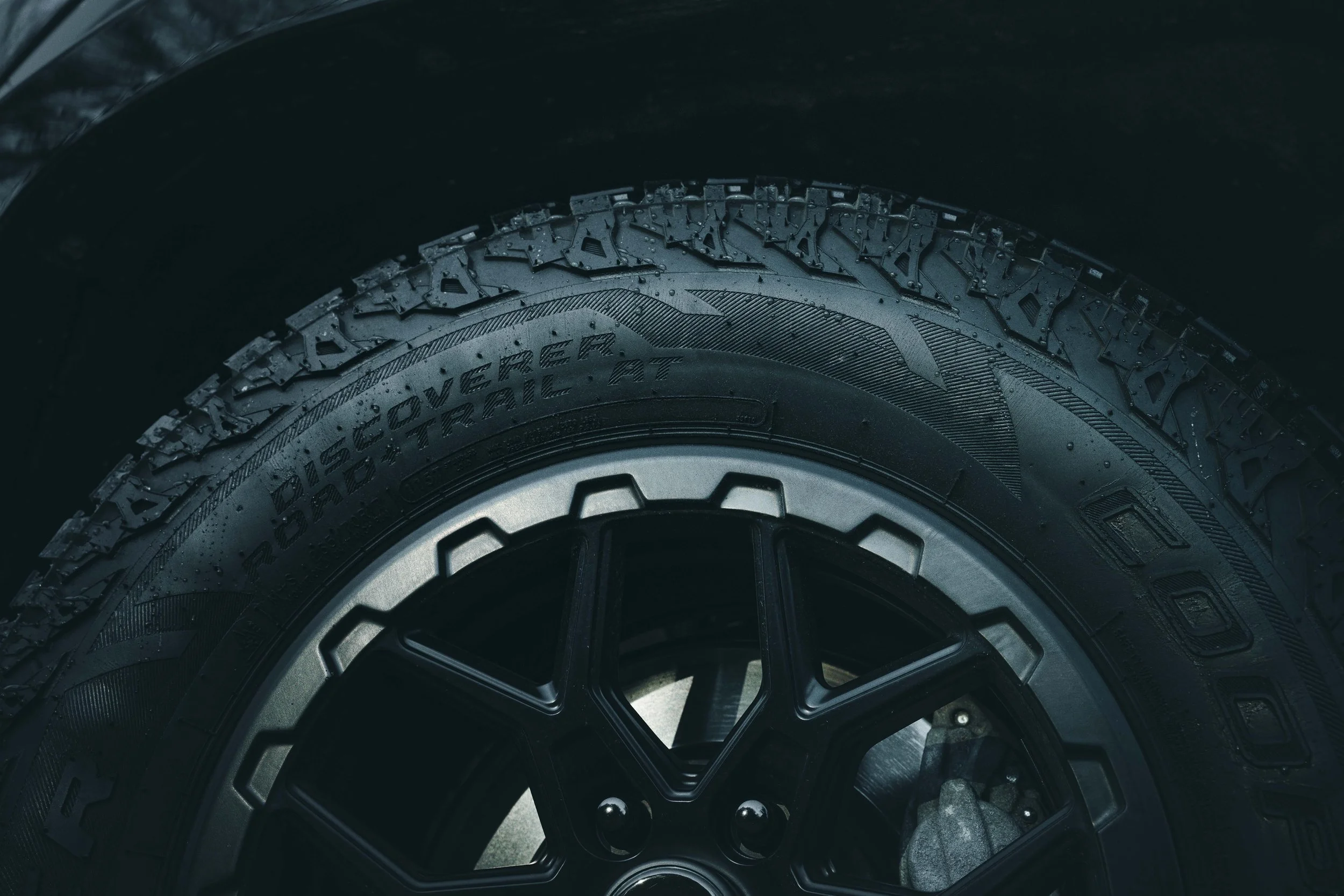 Close-up automotive detail photo of a Cooper tire and black wheel captured by Ian Jones of ISJDESIGNS for the Tamron 35-100mm review.