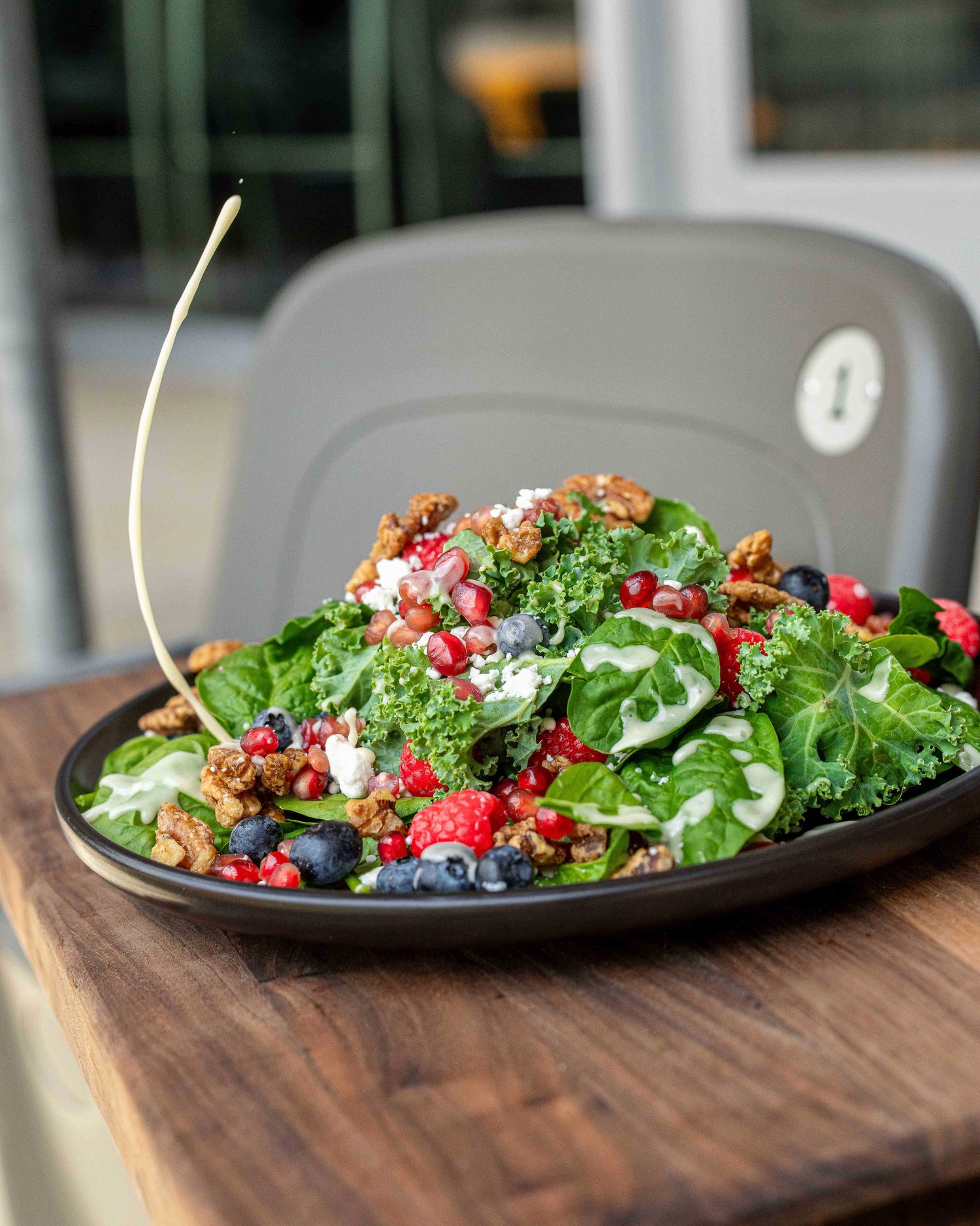 Fresh kale and spinach salad topped with raspberries, blueberries, pomegranate seeds, candied walnuts, crumbled cheese and creamy dressing, photographed by Ian Jones of ISJDESIGNS in Pittsburgh for Aramark Sports + Entertainment, an ISJDESIGNS food photography client.