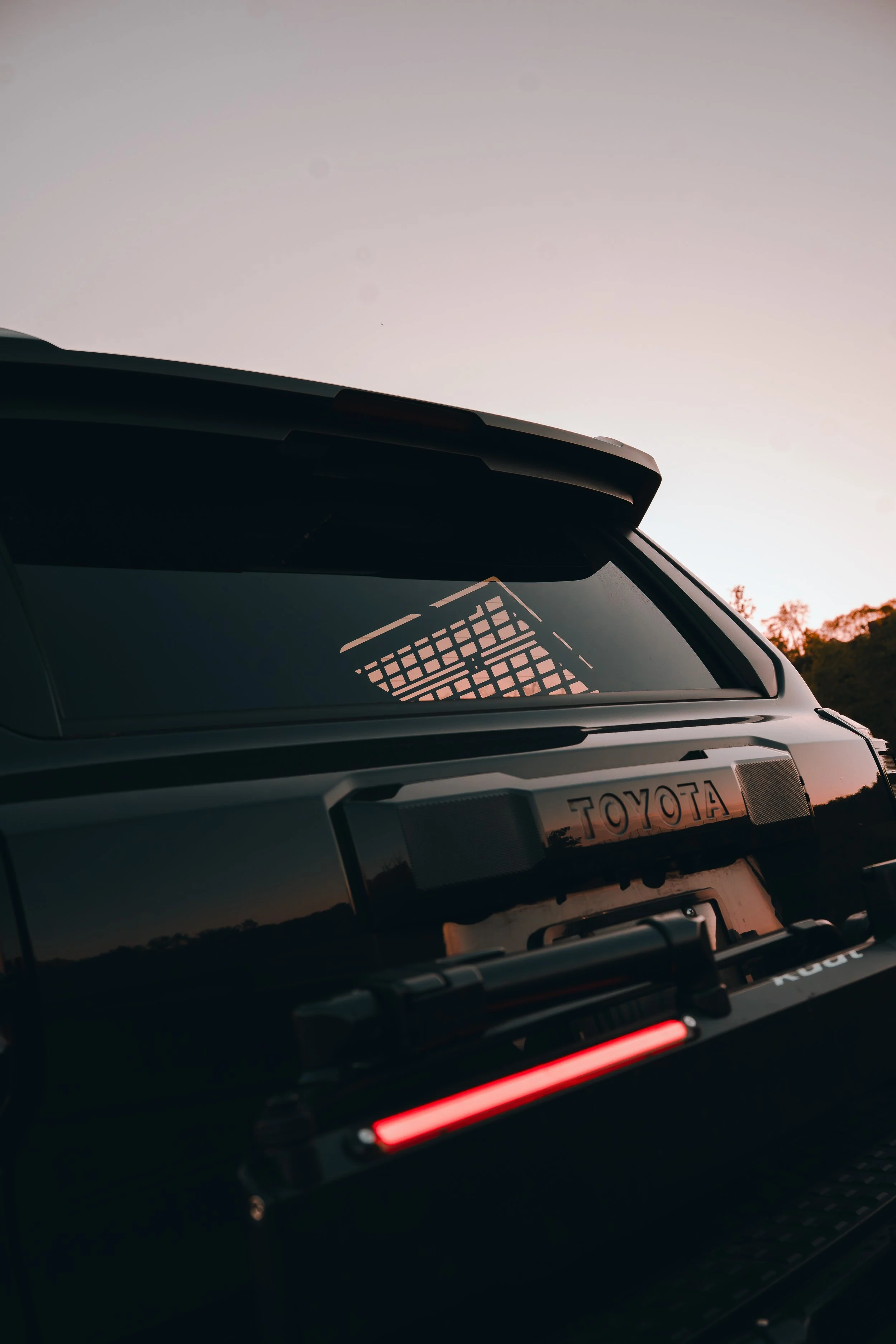 Close-up of the integrated LED tail lights and matte black design language of the Kuat Piston Pro X bike rack on Ian Jones' 2025 Toyota 4Runner TRD Sport, showing the premium powder coat finish and built-in lighting that differentiate the Piston Pro X from competing hitch racks.