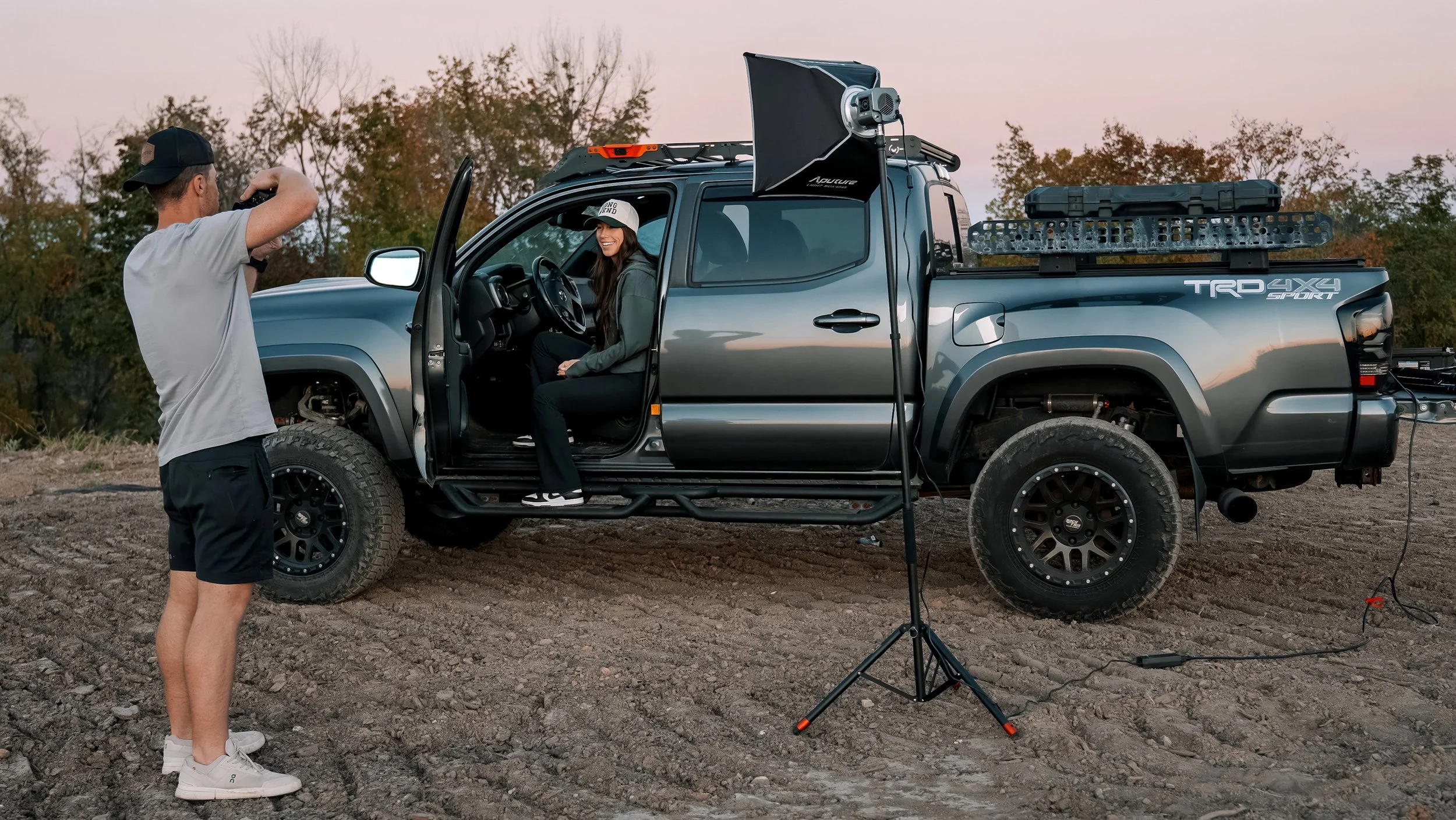Ian Jones photographing a portrait subject in a Toyota Tacoma using the ProMaster Air Support Light Stand during an outdoor automotive shoot.