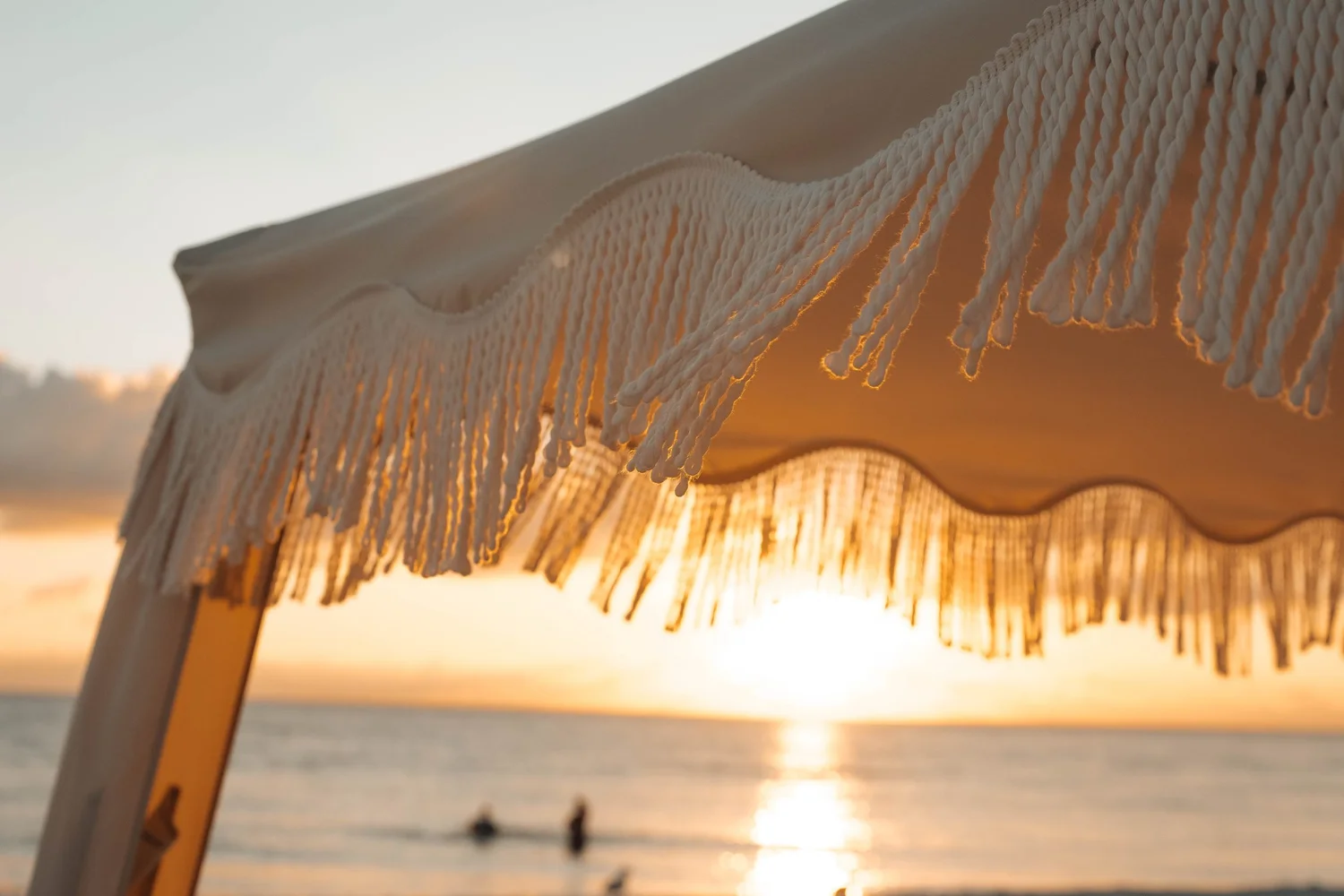 Fringed beachfront cabana framing a Gulf of Mexico sunset in Florida, atmospheric hospitality lifestyle photography for hotels, resorts, and destination brands.