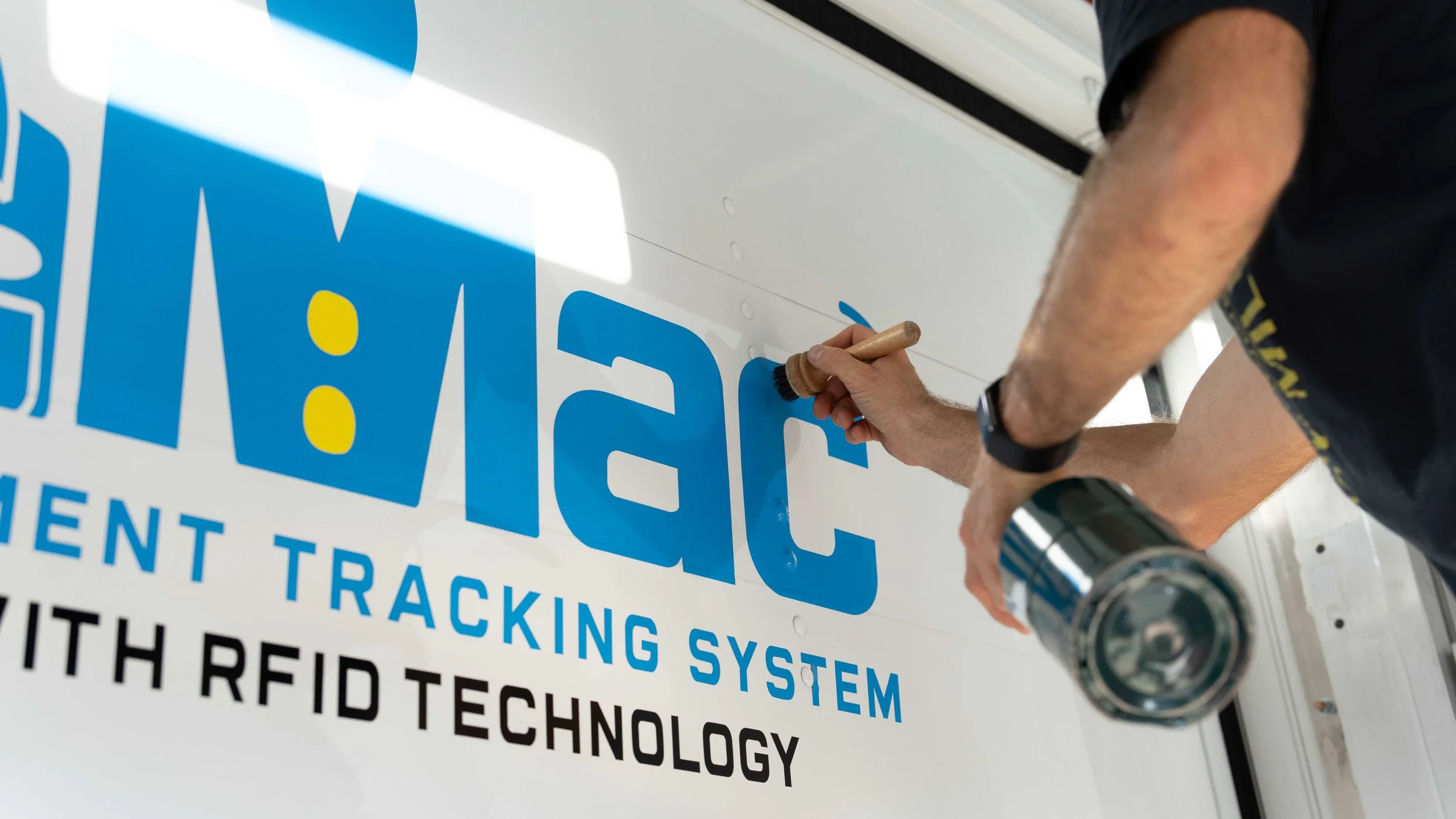 Pittsburgh commercial industrial photography by Ian Jones for ISJDESIGNS, showing an installer squeegeeing vinyl graphics onto a white delivery truck panel.