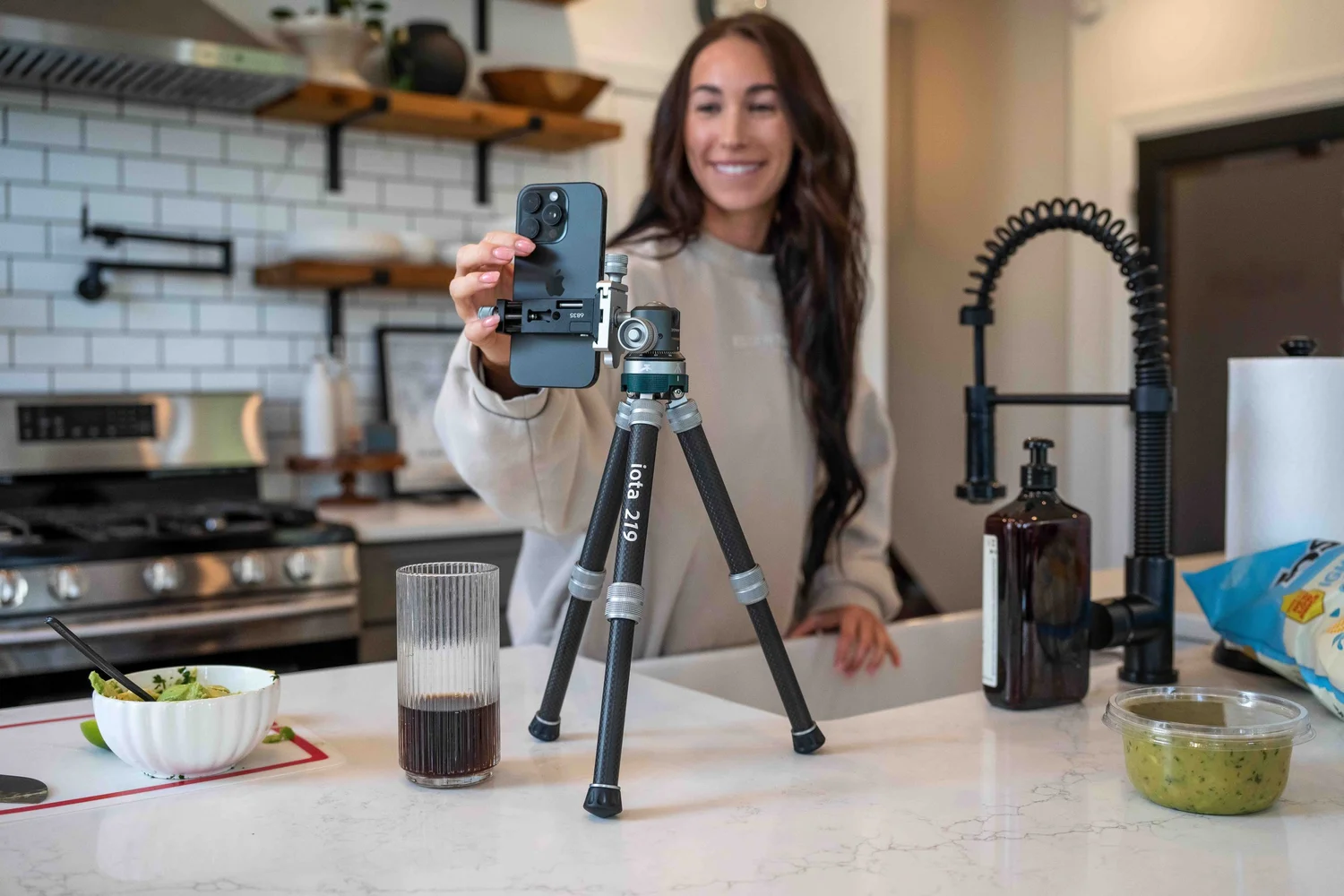 Creator framing an iPhone mounted on a ProMaster iota 219 carbon fiber tabletop tripod in a kitchen