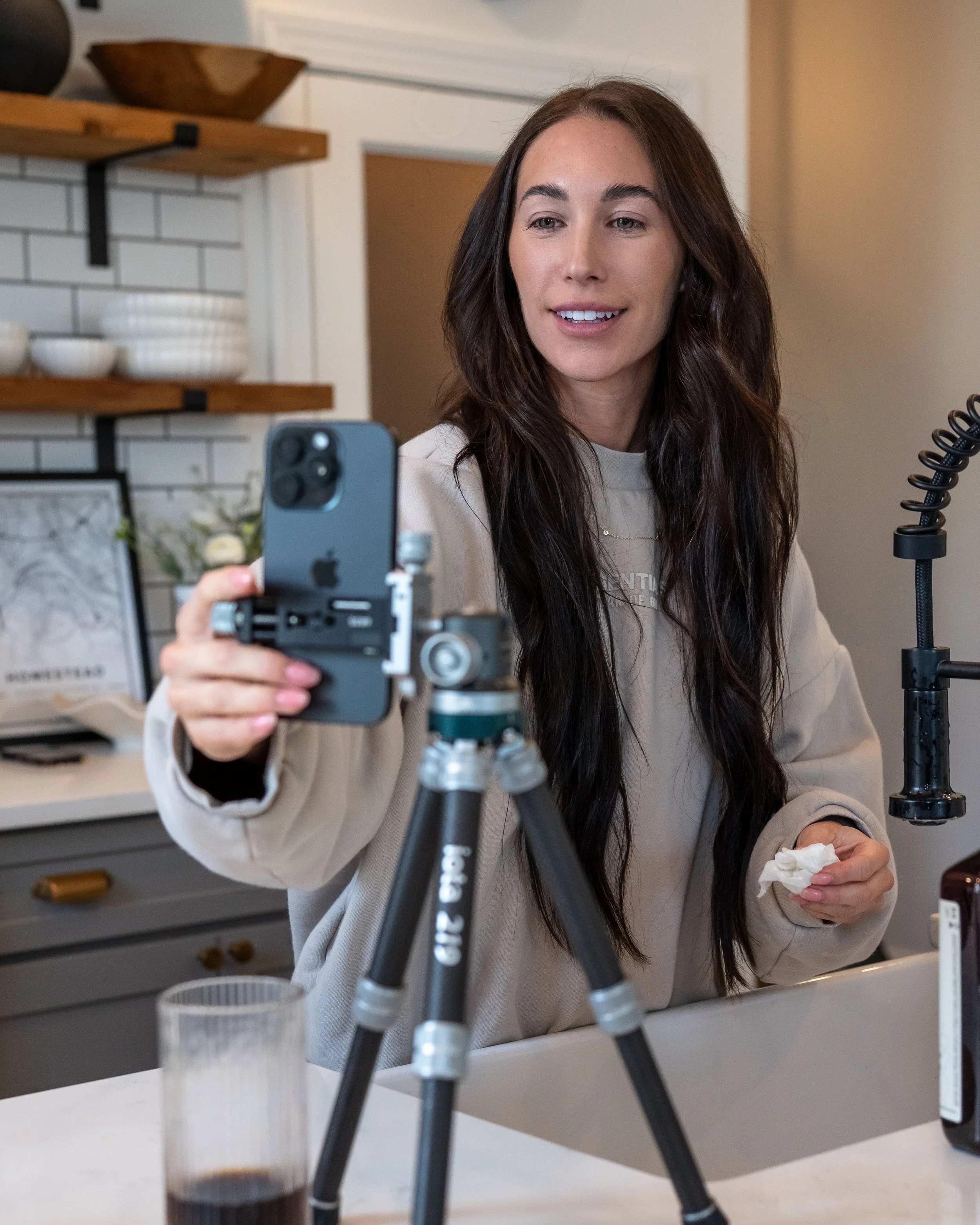 Behind-the-scenes kitchen content shoot by Ian Jones of ISJDESIGNS showing a creator filming food on a phone tripod, captured with the Tamron 35-100mm f/2.8 on the Sony a1.