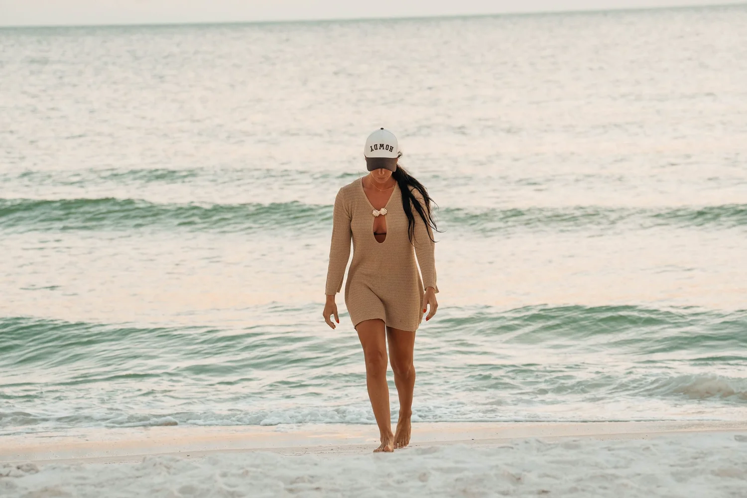 Woman in a knit cover-up walking out of turquoise Gulf water in Florida, travel and hospitality lifestyle photography for resort and destination campaigns.