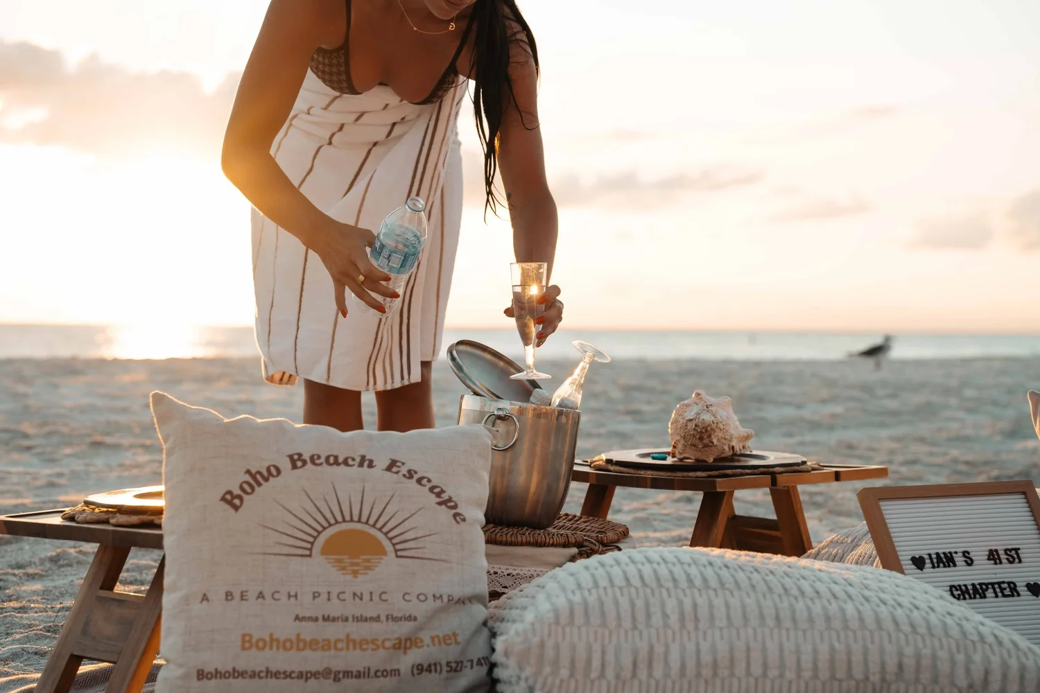 Woman setting glassware for a sunset beach picnic on Anna Maria Island, Florida, hospitality lifestyle photography for destination and experience marketing.