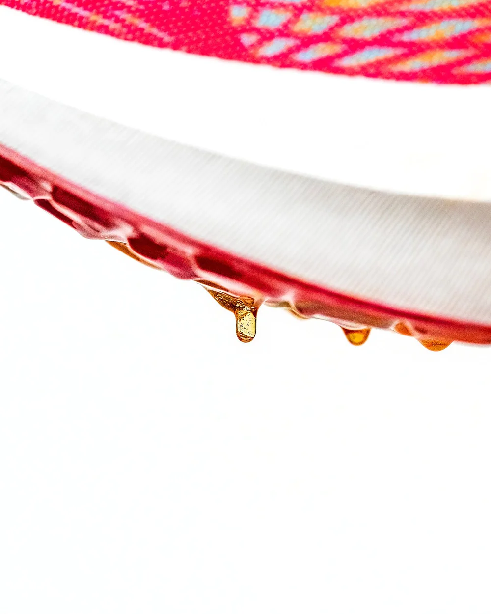 Macro product photography by Pittsburgh photographer Ian Jones for ISJDESIGNS, showing water droplets and sole detail on a John Geiger 005 Orange Burst sneaker.