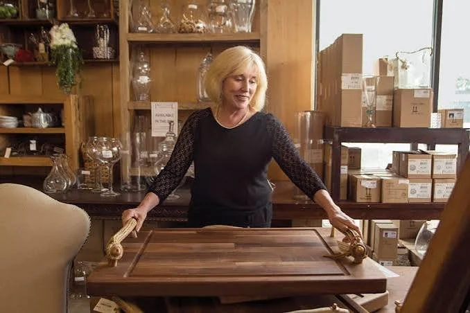Debbie Michael with a walnut serving tray in the Paul Michael Company showroom