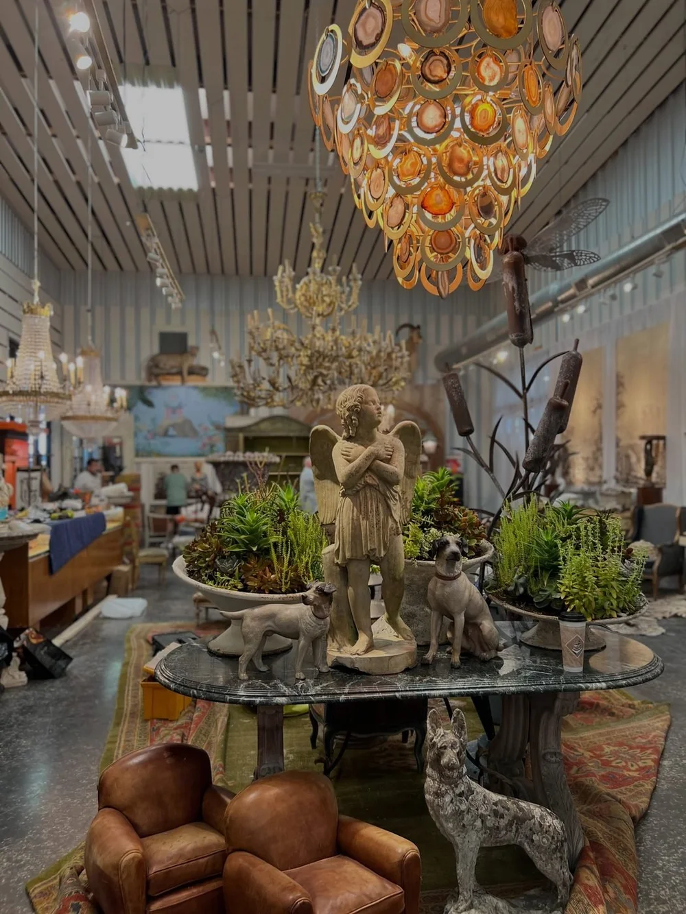 Agate chandelier hanging over a marble table set with garden statuary and succulents