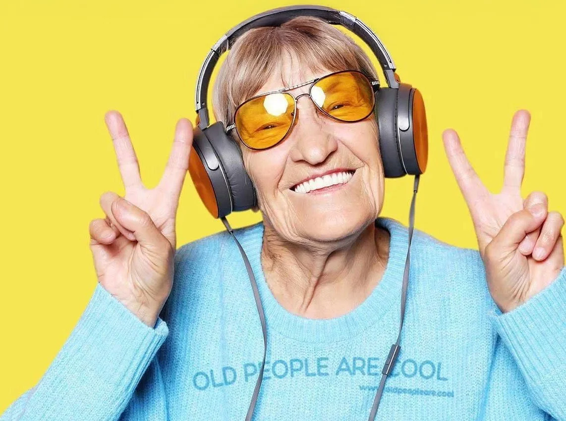 Happy senior woman wearing headphones and making peace signs